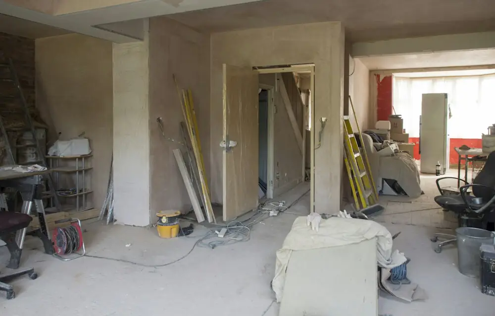 Tadilat sırasında sıvası yenilenmiş, boyaya hazırlanan bir daire odası; malzemeler ve aletler zeminde